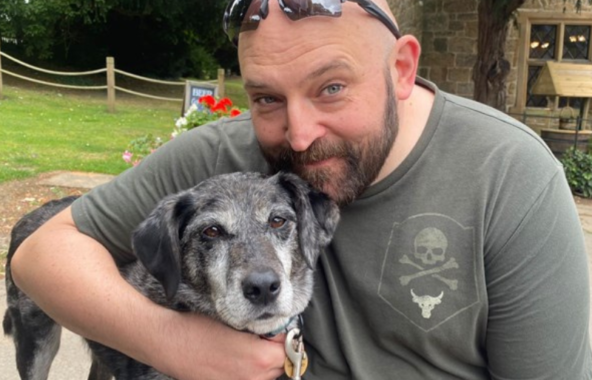 A photo of a fundraiser with their arm around their rescue dog.