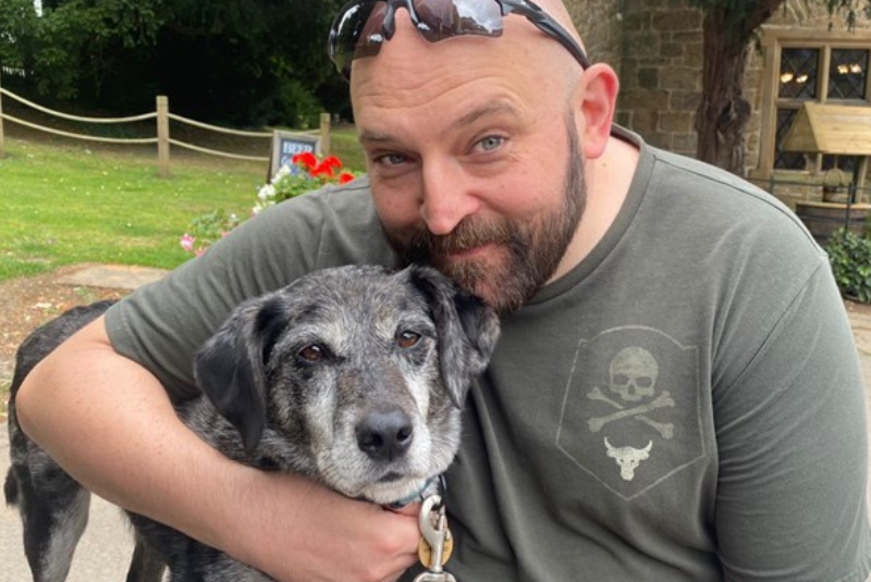 A photo of a fundraiser with their arm around their rescue dog.